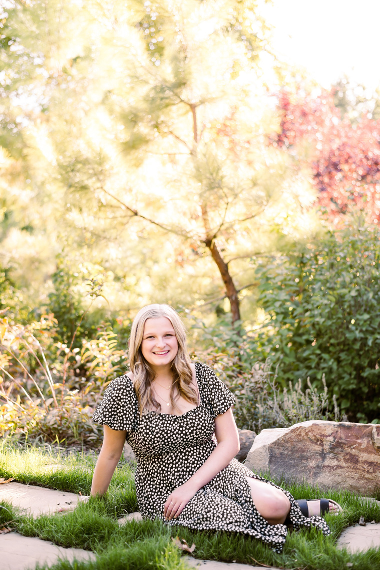 Blond high school senior girl sitting in among trees and plants at Myriad Gardens in downtown Oklahoma City