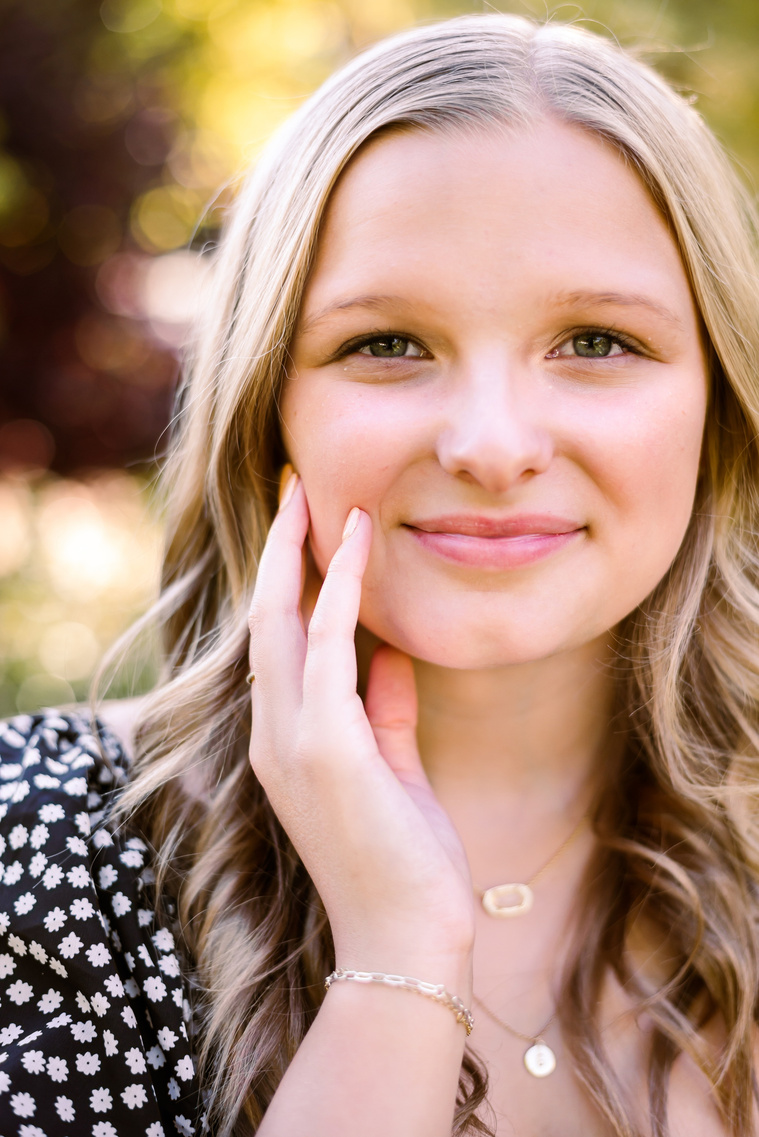 close up of blond high school senior girl wearing a dress resting her face in her hand at Myriad Gardens in downtown Oklahoma City