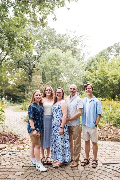 family photo of older kids standing together on a brick path with tall trees around them at Lendonwood Gardens in Grove Oklahoma