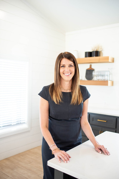 personal brand photo session of a female relator wearing a black dress standing in a kitchen with a warm smile in Newcastle, Oklahoma