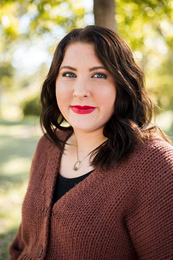 Head and shoulders portrait of a senior girl in a brown sweater smiling