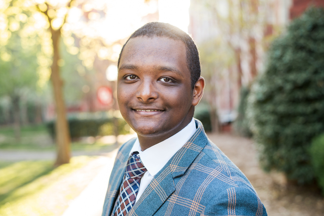 close up portrait of an african-american high school senior boy wearing a patterned suit and smiling on a sidewalk on the OU campus in Norman Oklahoma