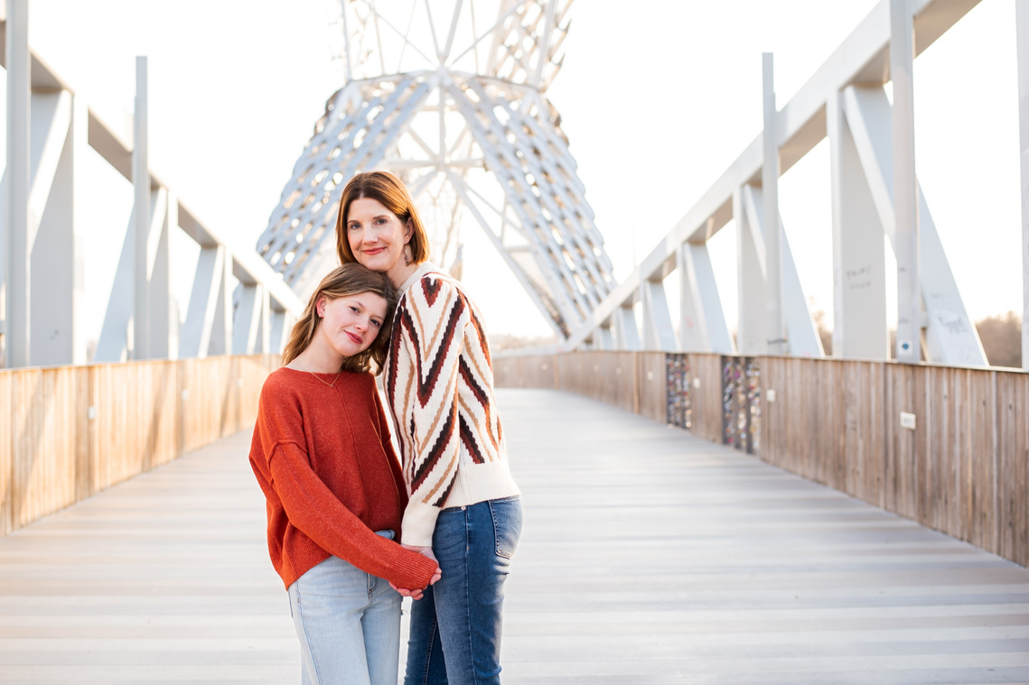 a mom and teen daughter hug and smile together on the Skydance Bridge in Scissortail Park in Oklahoma City