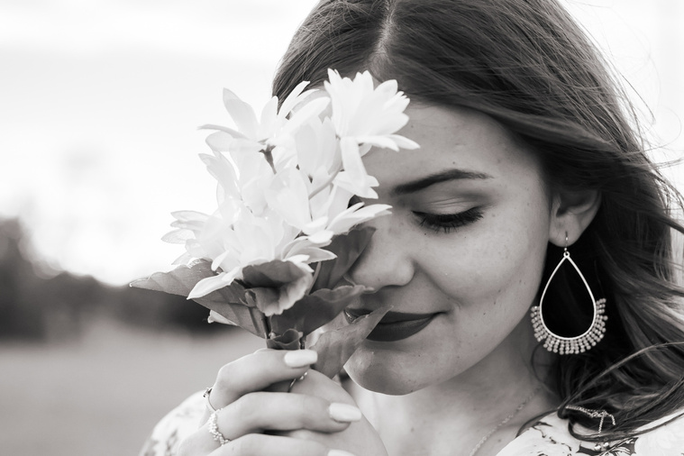 black and white close up portrait of a high school senior girl dressed in boho style holding a bouquet of daisies over half her face and looking down in Oklahoma City, Oklahoma