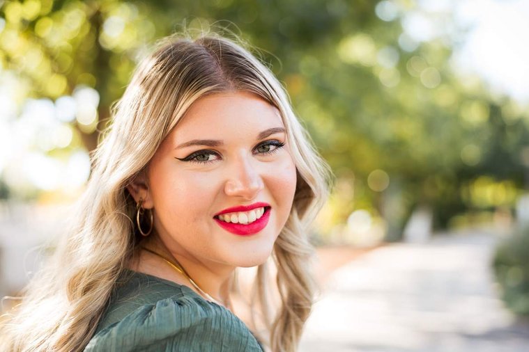 blond high school senior girl smiles brightly at Myriad Gardens in downtown Oklahoma City for senior portraits