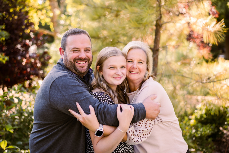 high school senior girl being hugged by her mom and dad at her senior photos at Myriad Gardens in downtown Oklahoma City