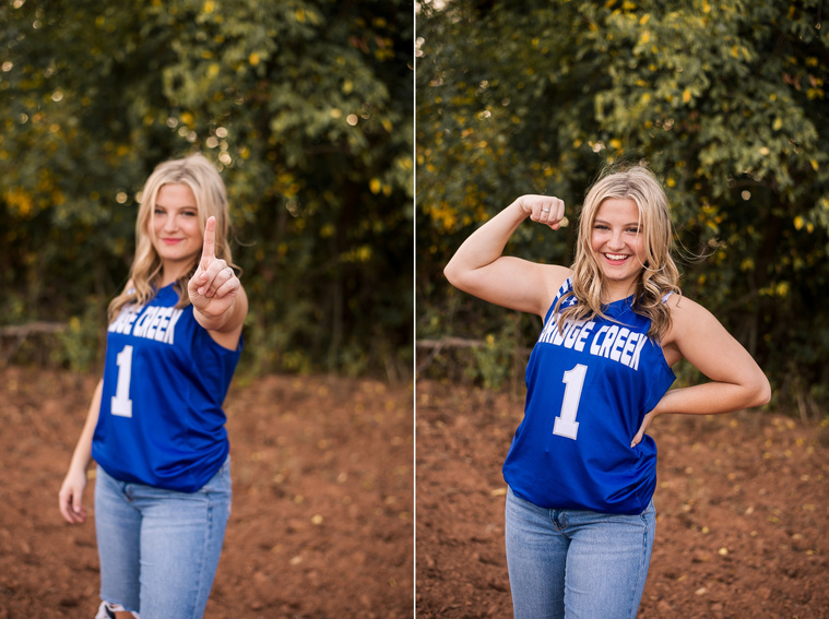 two images of a high school senior girl in her blue basketball jersey and jeans, showing her biceps and holding up a 1 with her fingers with a tree line behind her at her senior photo session