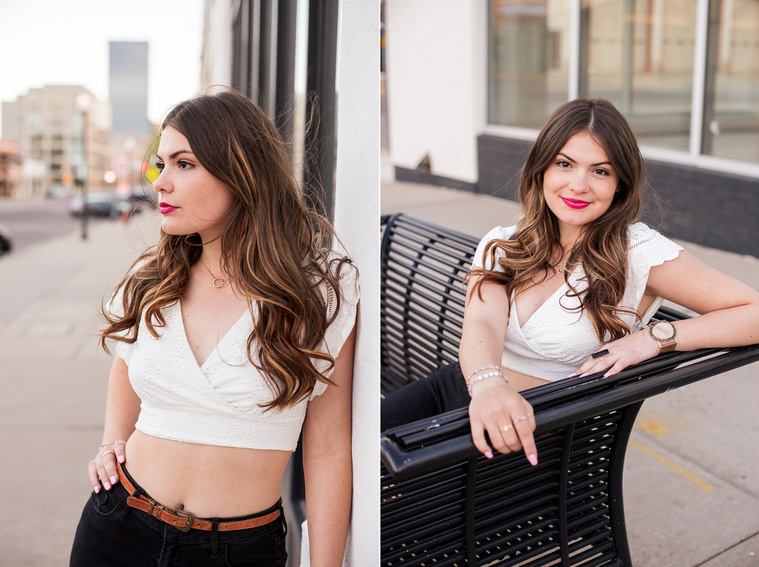 two photos of a high school senior girl with long brown hair wearing a white crop top and black jeans sitting and standing on the sidewalk against buildings in Automobile Alley in Oklahoma City, Oklahoma