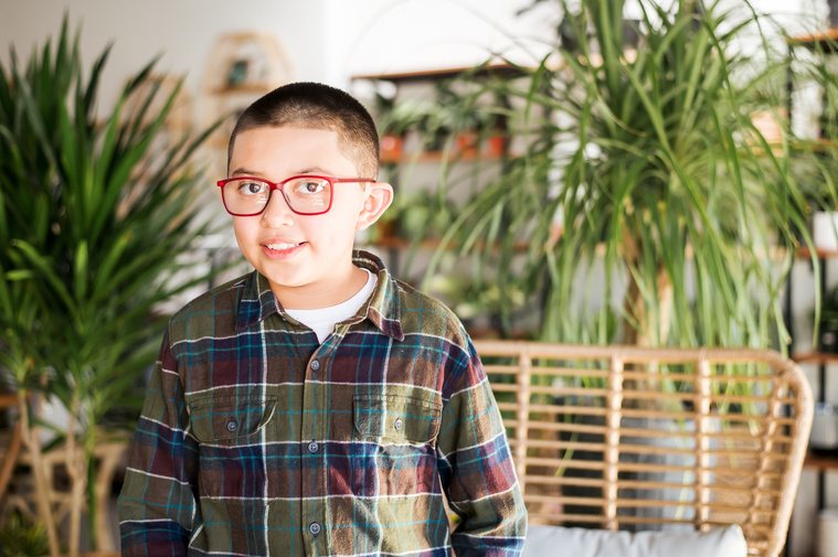 a young boy stands and smiles at a plant shop in Oklahoma City Oklahoma