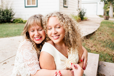 a mom and older teen daughter hug together closely on the front steps of their home in Norman, Oklahoma