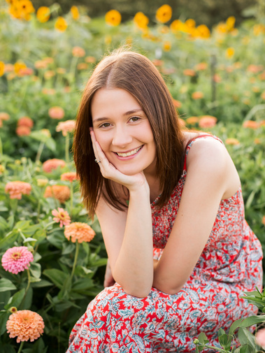 High school senior girl sits and smiles at a flower farm in Pocasset, Oklahoma