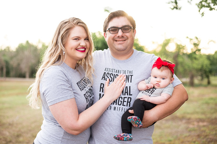 Mom and Dad hold their baby girl in the park wearing 