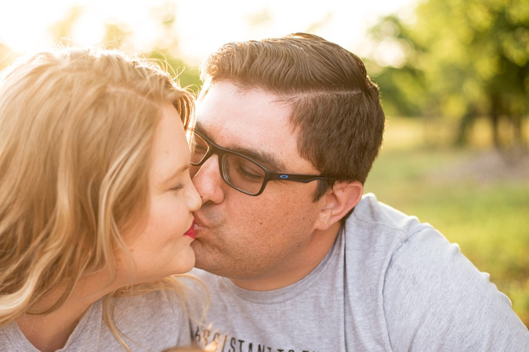 A young couple kiss lightly in the park.