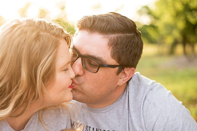 A young couple kiss lightly in the park.