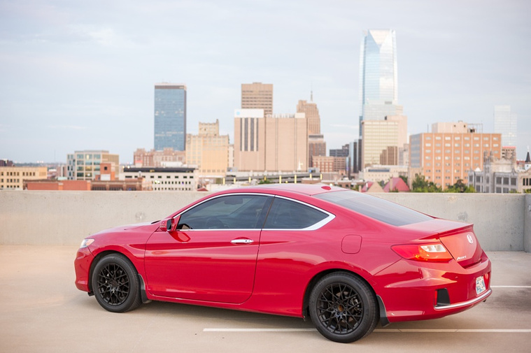 Red car parked on a parking garage rooftop with downtown Oklahoma City skyline behind it