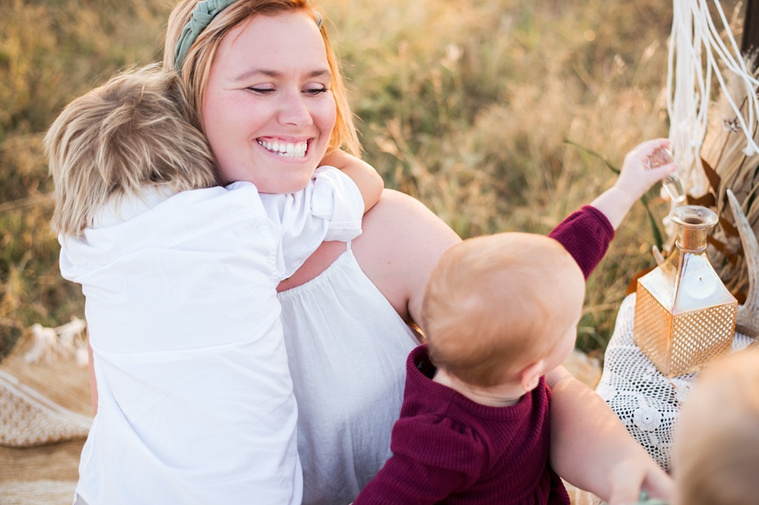 A mom and her young son and daughter hug and laugh in a field at a family photo session in Tuttle, Oklahoma