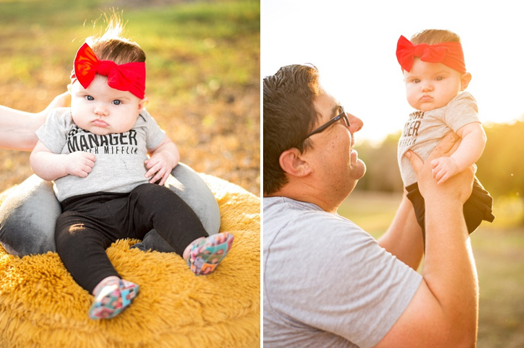 Dad holds his baby girl up in the sunshine, baby girls sits up on a pouf.