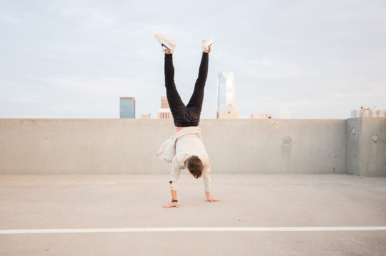 Headshots and portraits of a teen boy in downtown Oklahoma City. Doing a handstand on a Parking Garage Rooftop with OKC skyline in background.