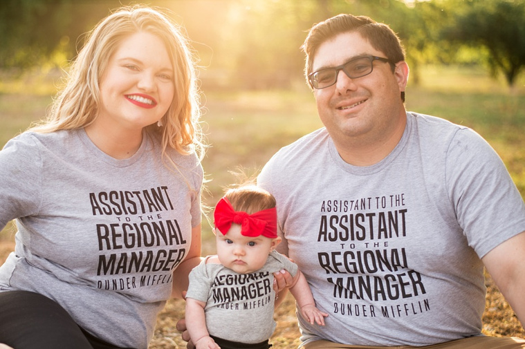 Mom and Dad hold their baby girl in the park wearing 