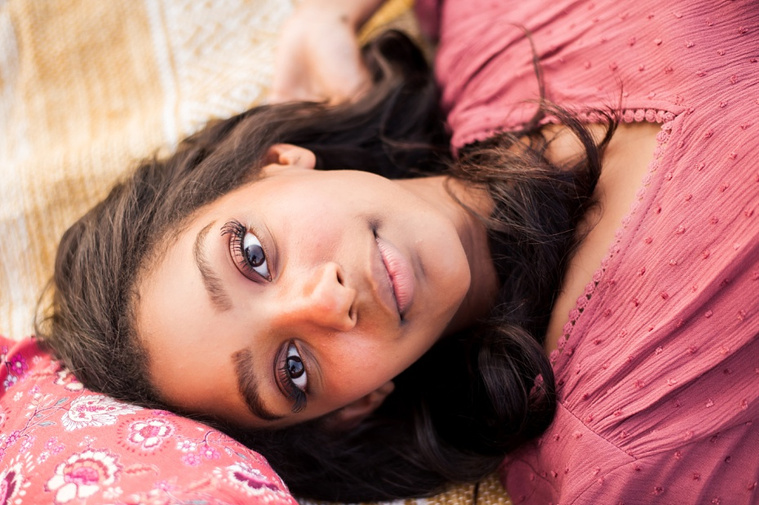A senior girl laying on a rug looking at camera in the country in Oklahoma