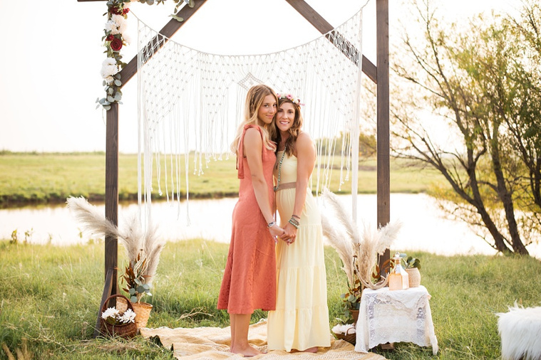 A mom and teen daughter dressed in boho style pose in front of boho decorations and a field and pond in the country in Oklahoma