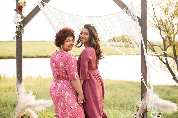 A mom and teen daughter dressed in boho style pose in front of boho decorations and a field and pond in the country in Oklahoma