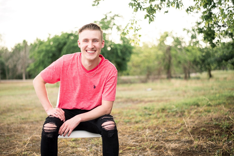 Teen boy sits in a chair casually in a park in Tuttle Oklahoma