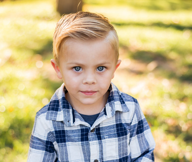 a young boy with blond hair and bright blue eyes looks at the camera  at Will Rogers Park in Oklahoma City, Oklahoma at a fall photo mini session by Cheryl Jackson Photography