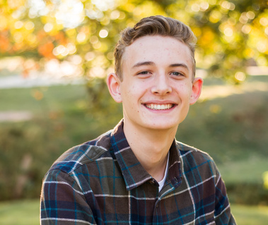Senior boy poses naturally and smiles at Will Rogers Park in Oklahoma City, Oklahoma at a fall photo mini session by Cheryl Jackson Photography