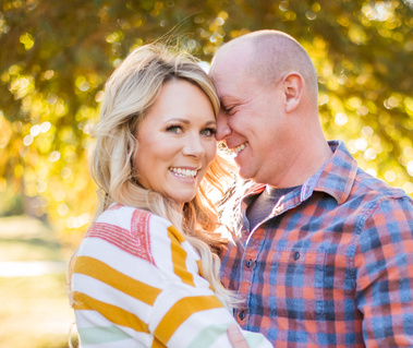 a husband and wife snuggle and smile at Will Rogers Park in Oklahoma City, Oklahoma at a fall photo mini session by Cheryl Jackson Photography