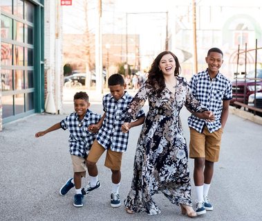 a mom and her three sons walk and laugh together on a street with buildings behind them in Oklahoma City