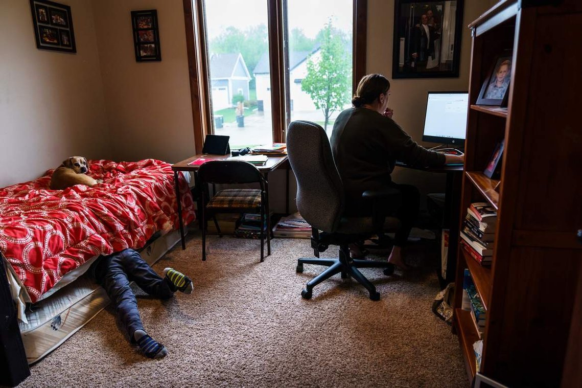 Faith Apel, a teacher at Mayo High School, updates grades for her students as her son Beau, 8, goofs around under the bed on Monday, May 18, 2020, at their home in Rochester. 