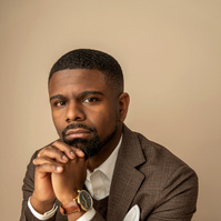 Man in earth tones in brown jacket on tan background. Clothing styling by Image Concepts.