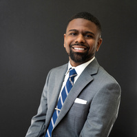 Man sitting in a chair in gray business suit. Clothing styling by Image Concepts. 