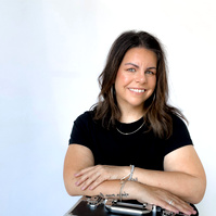 Image of professional woman with mobile skin care line sitting facing camera and smiling. 