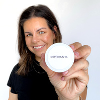 Image of professional woman in skin care clinic standing facing camera. Woman has skin care product in her hand. 
