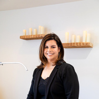 Image of professional woman in skin care clinic standing facing camera. with candles in background. 