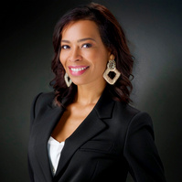Professionally save Brazilian woman in sport coat smiling into camera at 3/4 angle with black artistic background. 