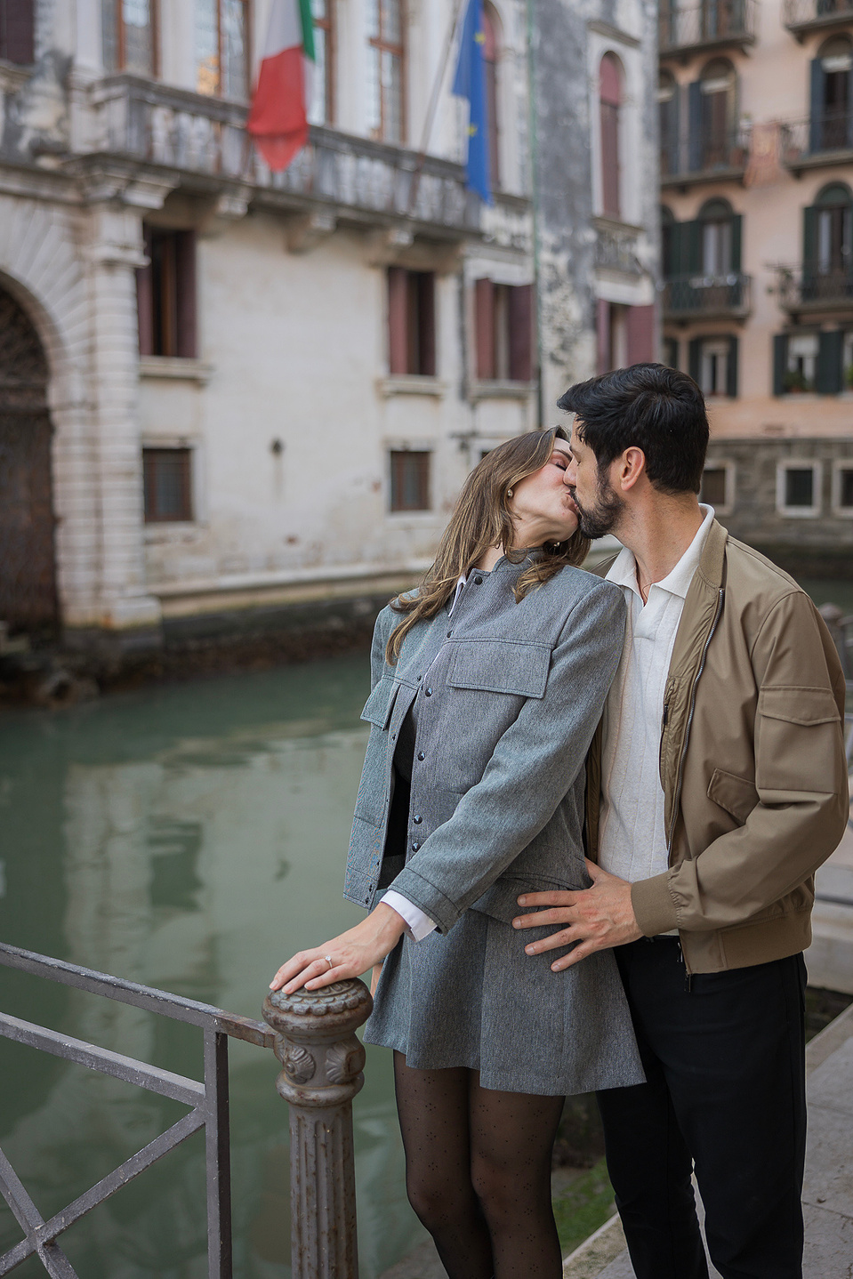 kissing couple on the side of a canal for an engagement photo shoot