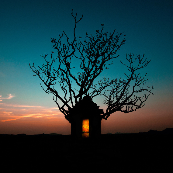 A shrine for hanuman, the monkey god in front of a silhouetted tree at dusk.