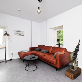 Wohnzimmer mit Ecksofa in Cognac und diveresen Eisenbahner Utensilien. 