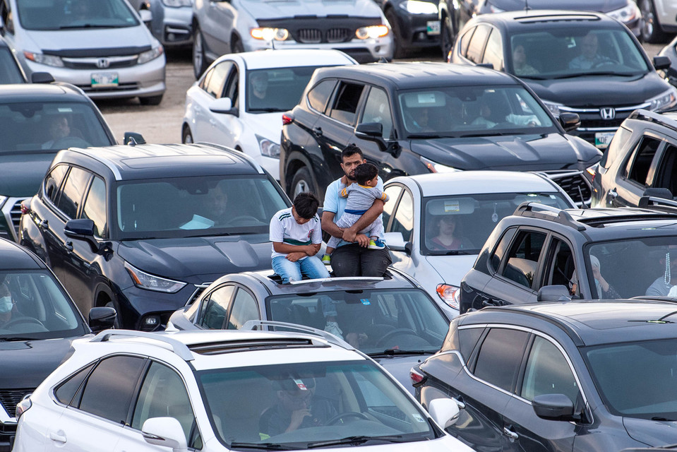 A family sits on top of their car while attending an outdoor vigil at a Winnipeg mosque.