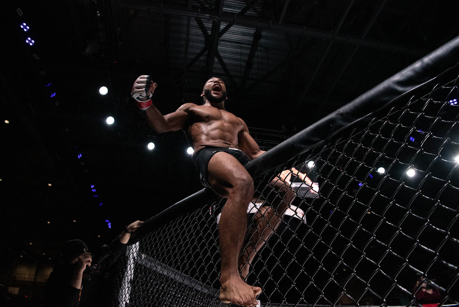 Teshay Gouthro celebrates atop the fenced walls of the octagon following his bantamweight fight victory over Kristian Bouchard during the BTC 13 Power event at the Meridian Centre on Nov. 20, 2021 in St. Catharines, Ont.