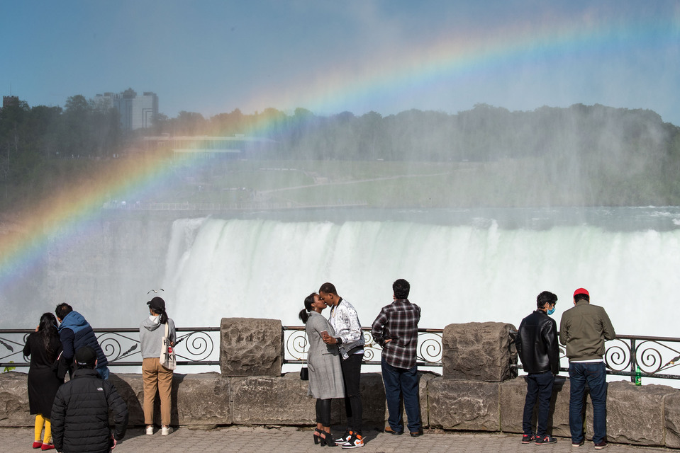 A couple kiss underneath a rainbow at the Niagara Falls.