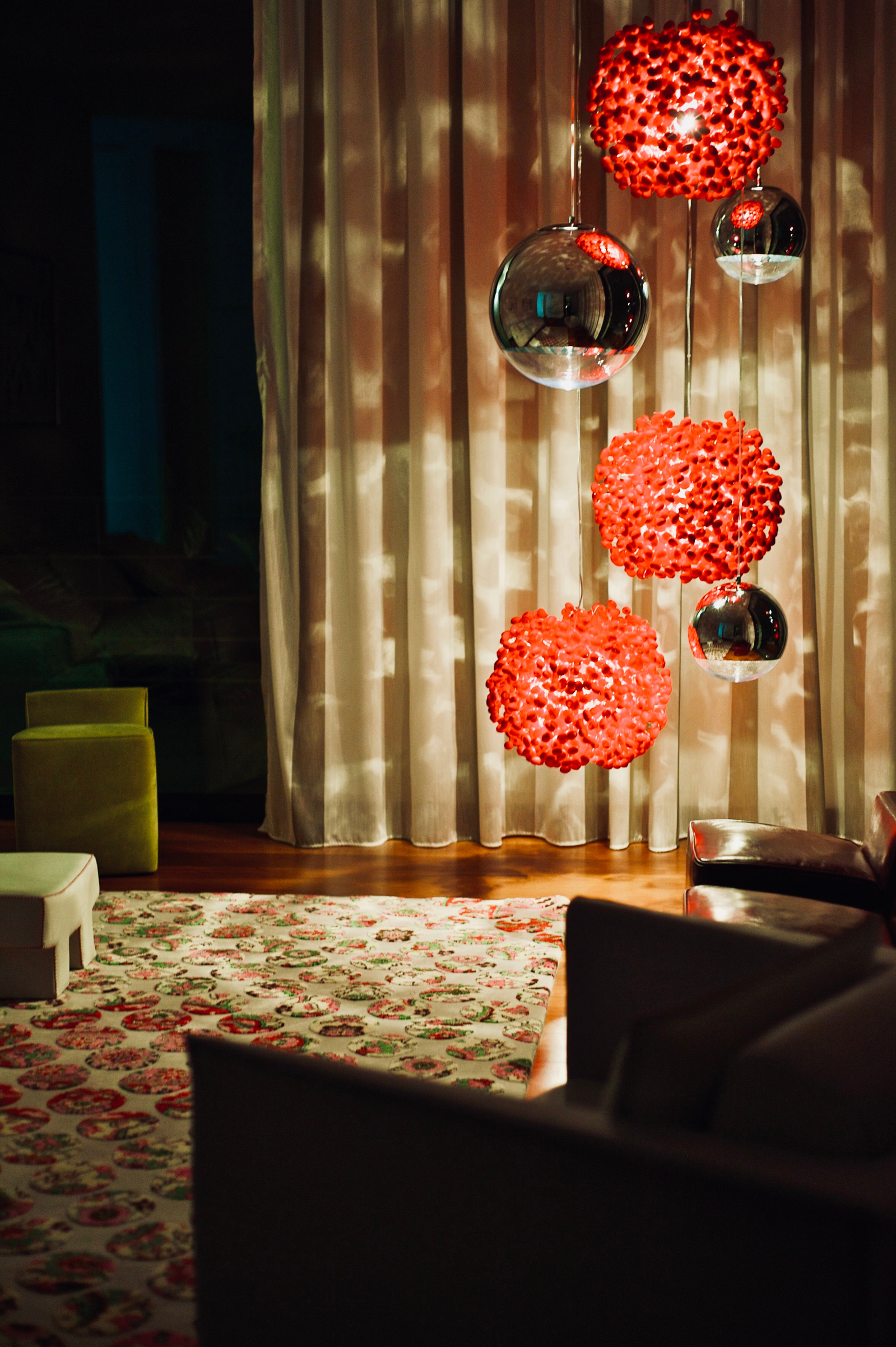 Loungebereich mit stimmungvoller Beleuchtung. Rote Kugelleuchten aus Seide, Angoworld. kombiniert mit Tom Dixon Mirror Ball Leuchte. Pendelleuchten, Lichteffekte. Sessel von Baxter. Drehsessel von Walter Knoll, Teppich I&I Italia
