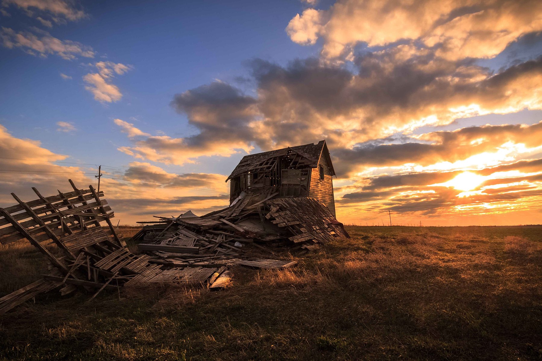 An old abandoned farmhouse lies in ruins against a dramatic sunset in Union Nebraska.