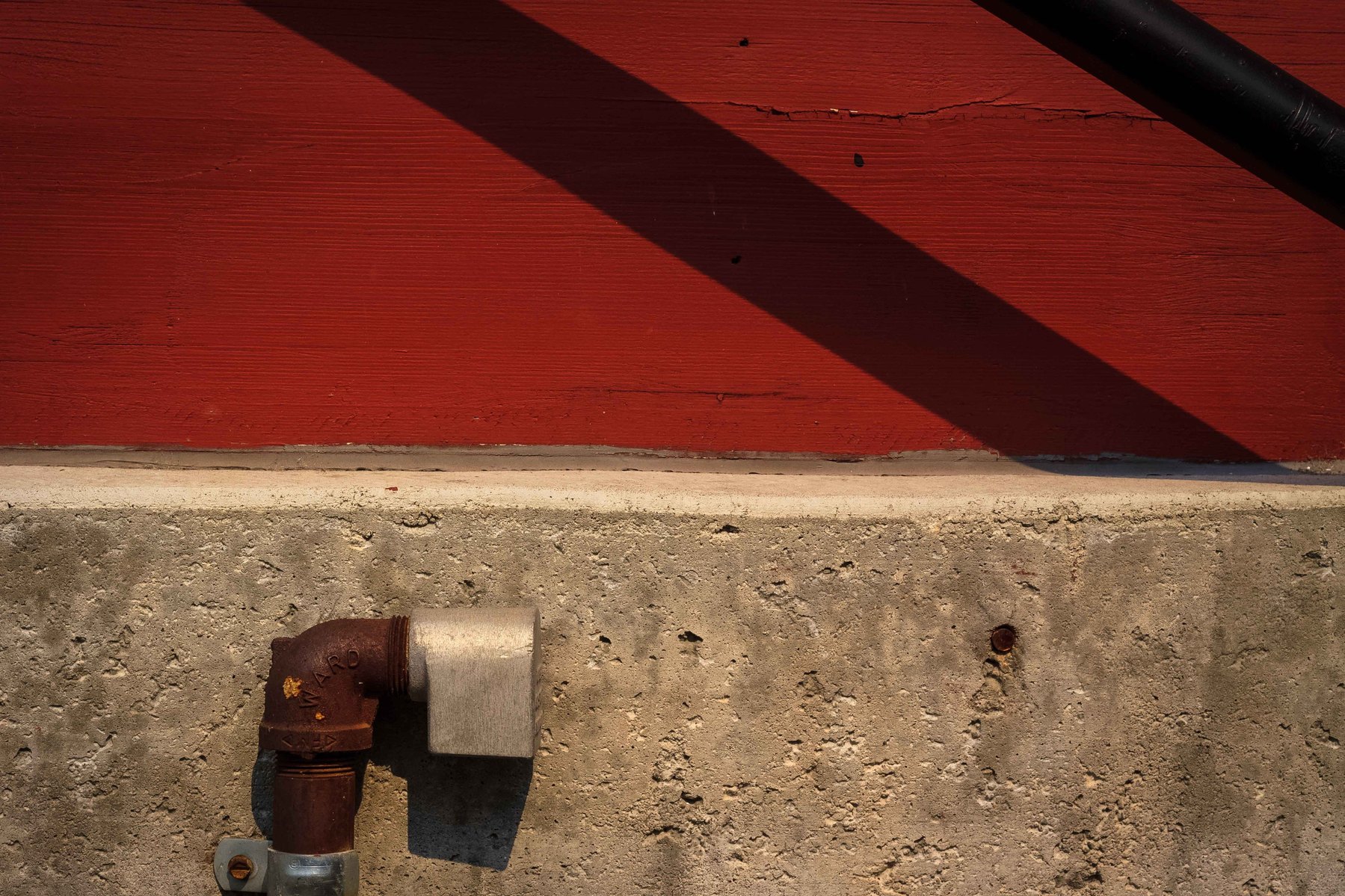 An abstract of a red wall with two solid shadow lines going through it.