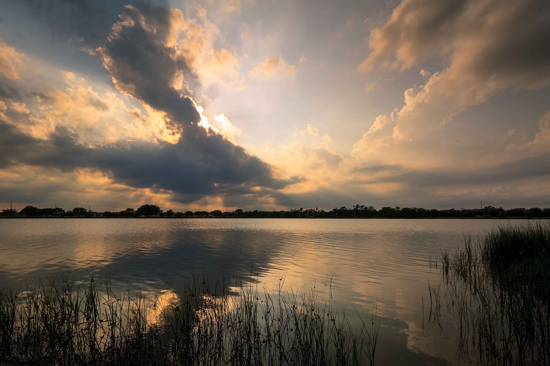 A still like reflects a dramatic cloudy sunset at Oak Lake in Nebraska.