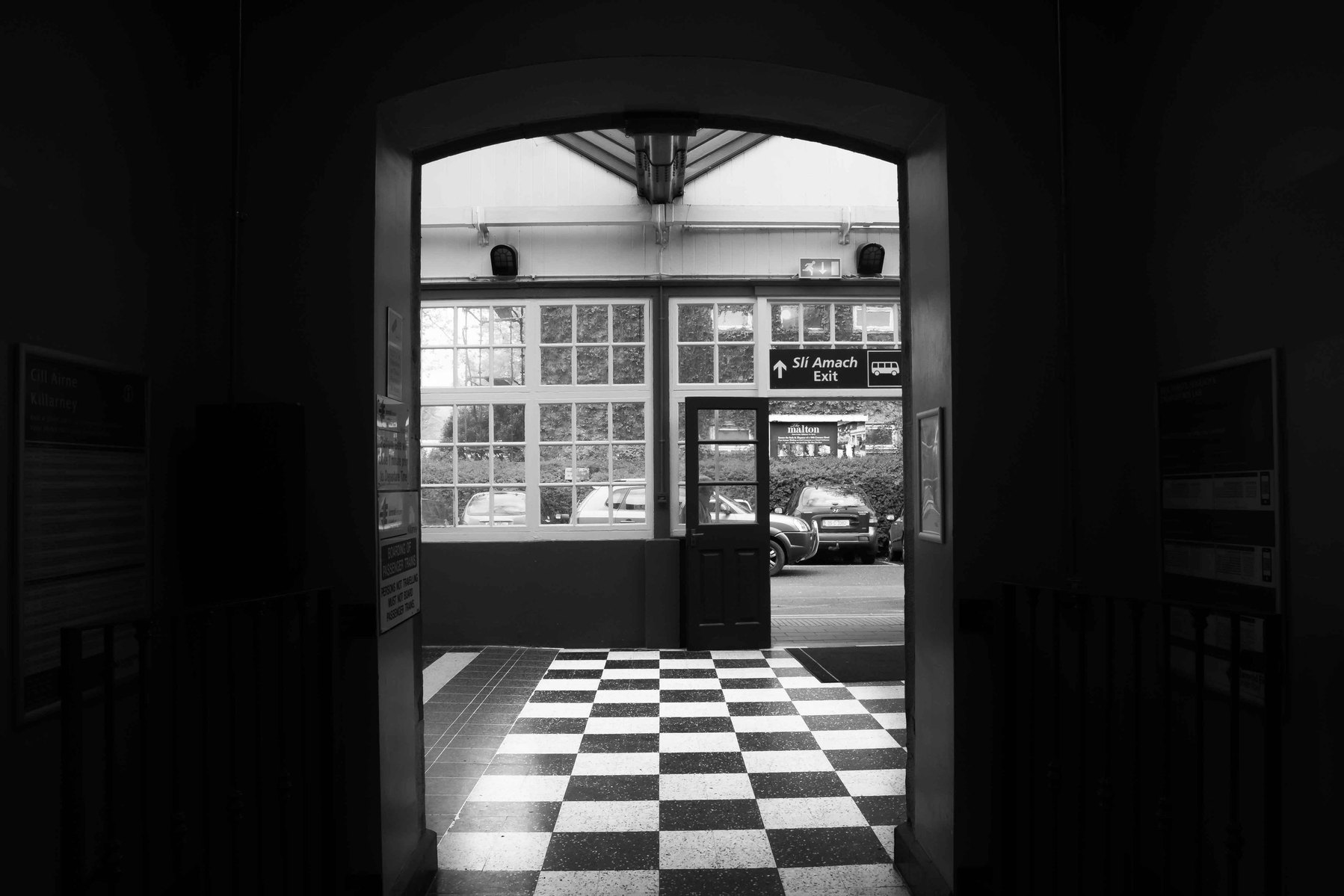 Looking out of a dark room into a light room with a checkered floor.
