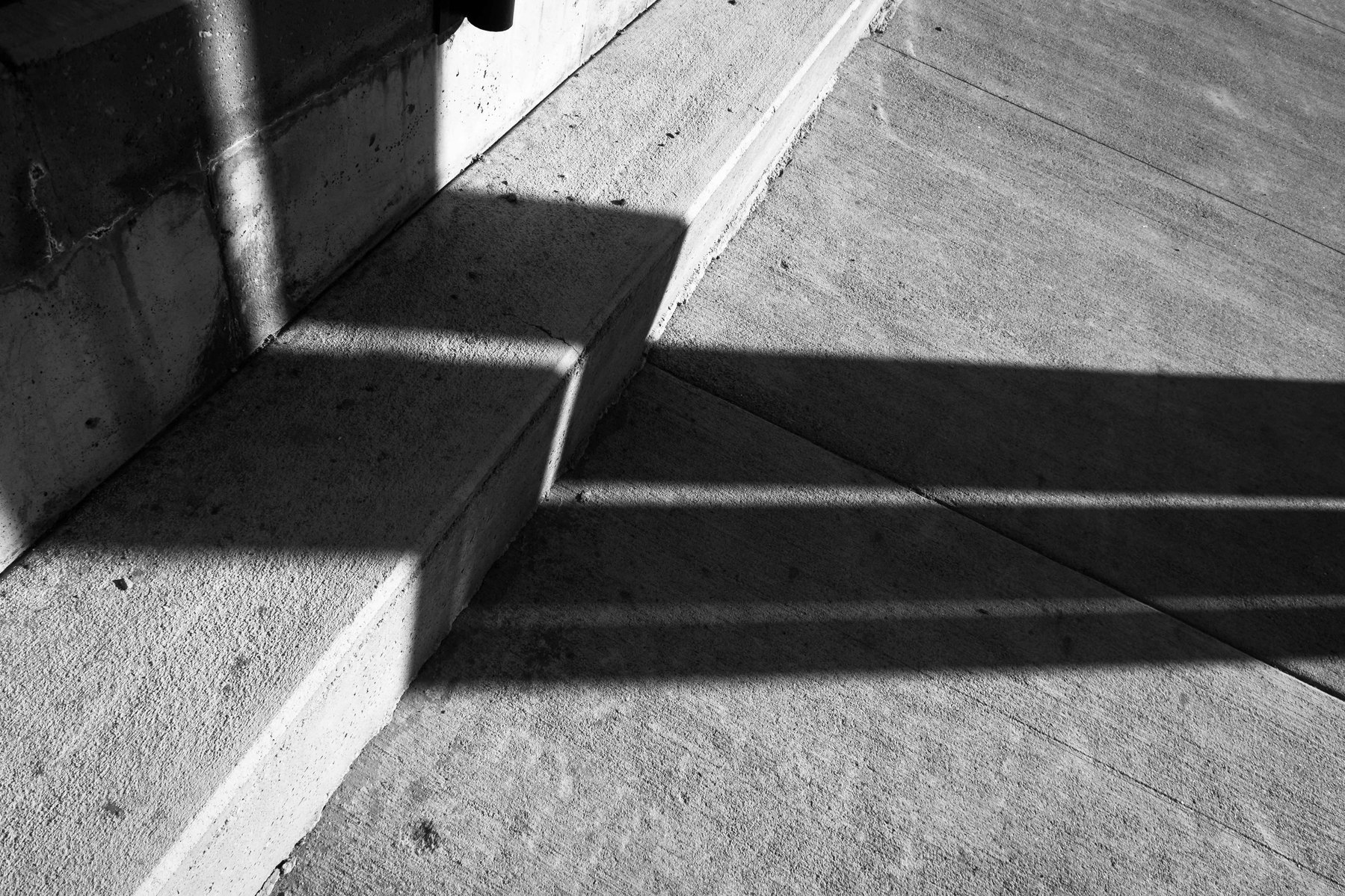 Shadows bend around corners on the street creating a unique pattern.
